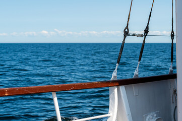Sailboat deck overlooks calm ocean waters under a clear blue sky in summer