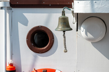 Bell and porthole on a boat during daylight, capturing marine ambiance and design elements