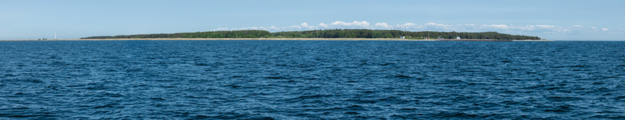 View of a peaceful coastline with lush greenery and calm blue waters on a sunny day