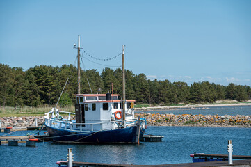 Fishing boat anchored at a serene dock surrounded by trees on a sunny day