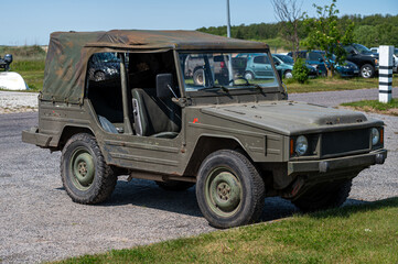Military style vehicle parked outdoors on a sunny day near a grassy area
