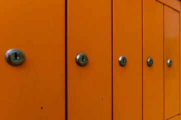 Bright orange mailboxes lined up in an urban setting during daylight hours