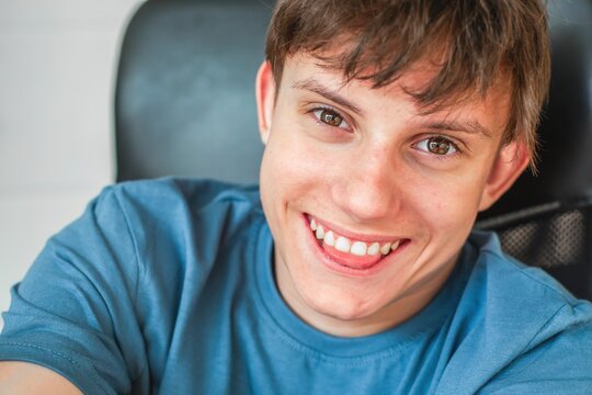 Portrait of a cheerful fourteen year old teenage boy with brown eyes, smiling playfully, sticking out the tip of his tongue