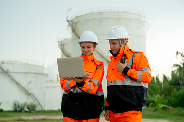 Two technician or gas factory workers discuss together in front of gas or petrochemical tank and...