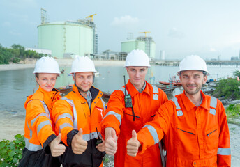 Close up group of petrochemical or gas factory workers or engineers show thumbs up with smiling and...