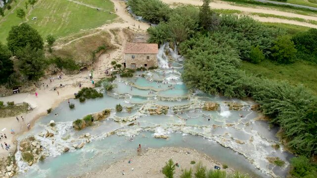 Aerial summer view of Terme di Saturnia, geothermal sulfur springs and natural spa with waterfalls at Saturnia thermal baths. People bathing at Cascate del Mulino, Grosseto, Tuscany, Italy.