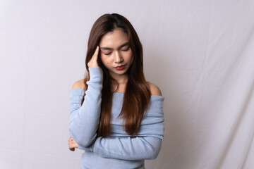Beautiful blonde Asian woman wearing light blue off-shoulder top having headache, holding head and closing her eyes, isolated on white background.