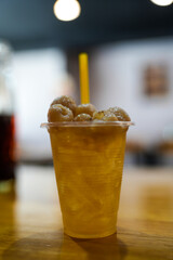 A refreshing longan drink served in a glass with ice on wood table.