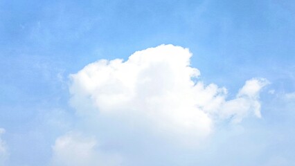A serene and expansive view of a bright blue sky dotted with soft, fluffy white cumulus clouds