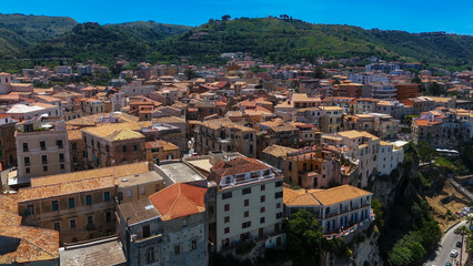 Panoramic view of Tropea, a charming town perched on a cliff, featuring traditional houses with red...