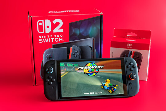 Fukuoka, Japan - june 7, 2025 : nintendo switch 2 game console running 2025 famous game Mario Kart world and console and controllers packaging isolated on red background