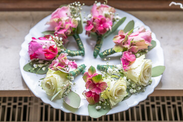 Small stylish boutonnieres on white marble plate, flat lay colorful many groom
