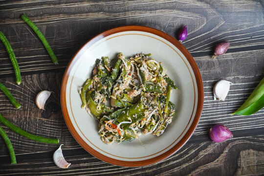 authentic local salad urap a classic Indonesian dish made from assorted vegetables, grated coconut, and aromatic spices on wooden background with raw ingredients, top view