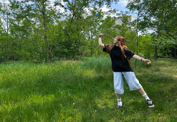 Teen girl in mid-air while playing badminton in sunny green meadow. Youth outdoor activity in summer park. Active girl enjoying outdoor activity in nature, summer lifestyle concept.