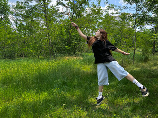 Teen girl in mid-air while playing badminton in sunny green meadow. Youth outdoor activity in summer park. Active girl enjoying outdoor activity in nature, summer lifestyle concept.