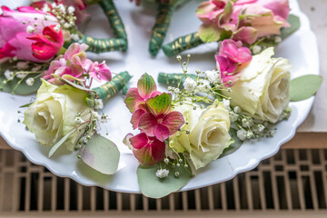 Small stylish boutonnieres on white marble plate, flat lay colorful many groom