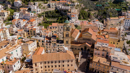 Aerial close-up of the historic heart of Amalfi, Italy, featuring the iconic Cathedral of Saint Andrew with its bell tower, surrounded by charming Mediterranean architecture