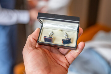 Man groom tying cufflinks on shirt sleeves getting dressed with closeup of hands no face