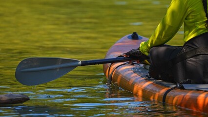 Lake Manitou, Manitoulin Island, woman sail on a SUP boards with special sport equipment, wet suit and life jacket for paddling. Stand up paddle boarding active recreation leisure and sport at lake.