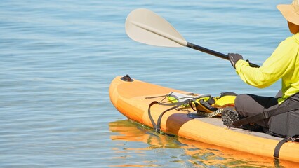Close up of woman in life jacket and on SUP board exercising at lake water. Paddleboard training and sport on paddle SUP board at sunny summer day. North America, Canada.