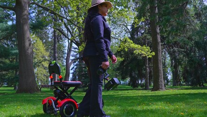 A female videographer person with physical disability using and riding a three wheel wheelchair or e scooter for video recording and content creating. Freedom and independence concept.