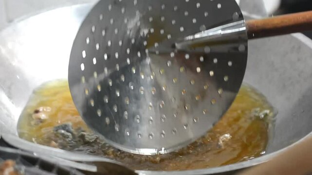 Detailed photo of the process of frying crackers in hot oil. Steam and oil bubbles are clearly visible as the crackers begin to expand, creating an authentic traditional kitchen atmosphere.