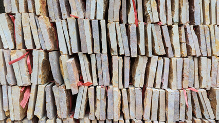 Stacked stone tiles with rustic texture and red ties, forming a natural geometric pattern