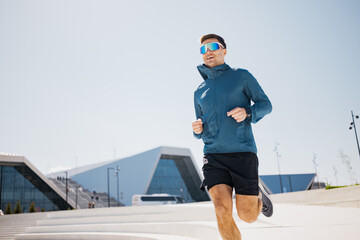 Dynamic Runner in Sleek Athletic Wear Sprinting With Determination Against a Modern Architectural...
