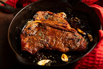 Close up of a juicy cooked 16oz T-bone steak in a cast iron skillet at home 