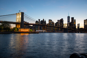 Fototapeta premium Dramatic Manhattan Skyline at night featuring the Brooklyn Bridge, New York, USA