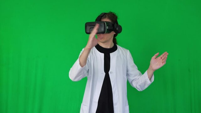  A mid-shot captures an immersive and futuristic mood as a person in a white lab coat and VR headset makes hand gestures, suggesting virtual reality interaction or gaming, green screen background