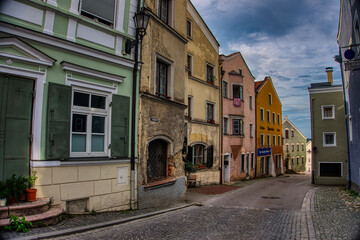 Charming street scene in Kraiburg am Inn, Germany, with pastel-colored stucco buildings, traditional shutters, and cobblestone pavement. A picturesque look into Bavarian small-town heritage.