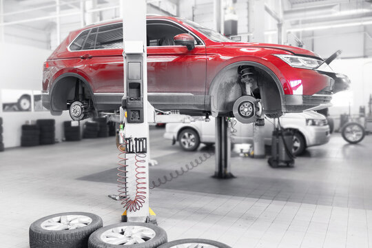 Red suv lifted for wheel service in modern auto repair garage