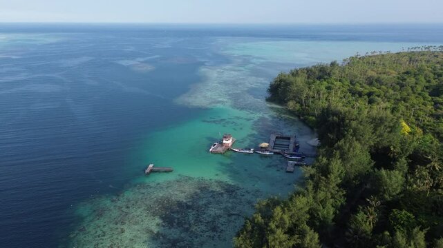 Aerial shot pan of a drone flying above a tropical island with crystal clear waters and an over water bungalow complex in the island of Karimun, Java, Indonesia