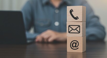 A stack of  blocks with a phone, adress and email icons on them.