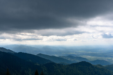 Obraz premium top view from mountain ladder landscape with clouds in summer carpathians romania with lights below clouds and green forests