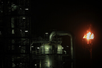 A gas flare at an oil refinery with lighting and dark Background	