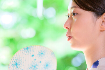 浴衣姿で扇子を持ち涼しげな表情を見せる女性の夏の瞬間