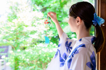 風鈴を手にする浴衣姿の女性の後ろ姿が映す夏の涼やかさ
