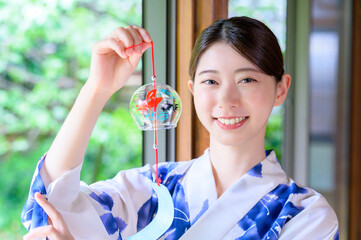 風鈴を手に爽やかな笑顔を見せる浴衣姿の女性