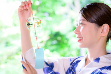 風鈴を掲げて微笑む浴衣姿の女性の夏のひととき