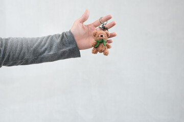 hand holding cute bear keychain in white background
