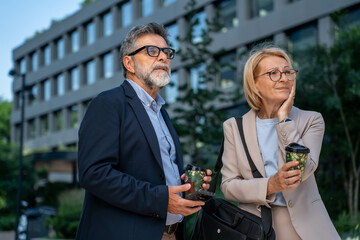 Concerned business professionals standing outside office building in urban business area