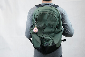 model man wearing bag showing off his cute pig keychain in white background