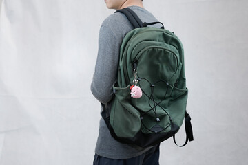 model man wearing bag showing off his cute pig keychain in white background