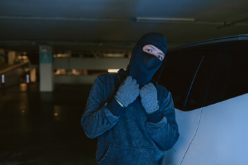 Mysterious figure in a parking garage wearing a mask, preparing for an uncertain activity at night