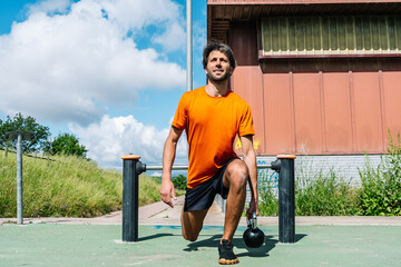 Sportsman doing lunges with kettlebell in calisthenics park