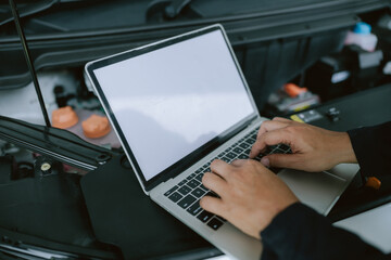 Mechanic performs diagnostics using laptop on car engine during maintenance at an automotive...