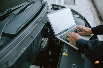 Mechanic performs diagnostics using laptop on car engine during maintenance at an automotive...
