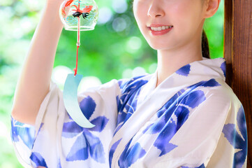 浴衣姿の女性が涼しげな表情で風鈴を手に取る夏の一コマ